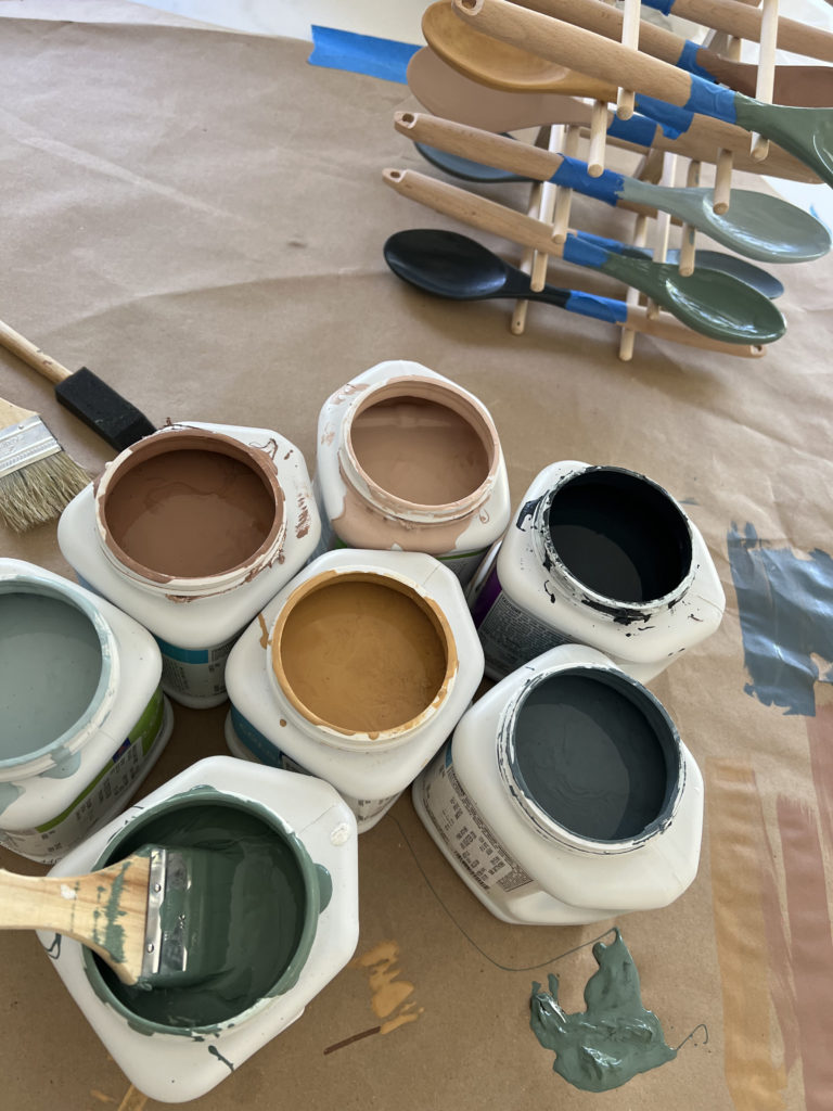 An array of paint cans in different colors: gold, blues, and tans