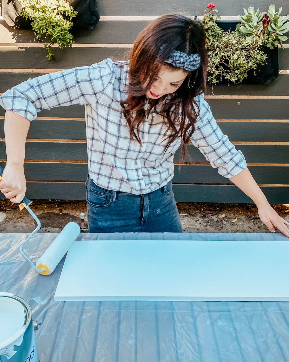 Anita rolls paint onto the sanded melamine surface