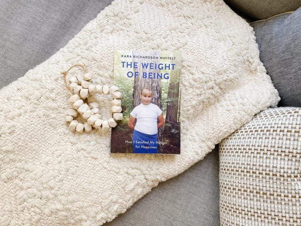 Book 'The Weight of Being' laid on a blanket with mandala beads