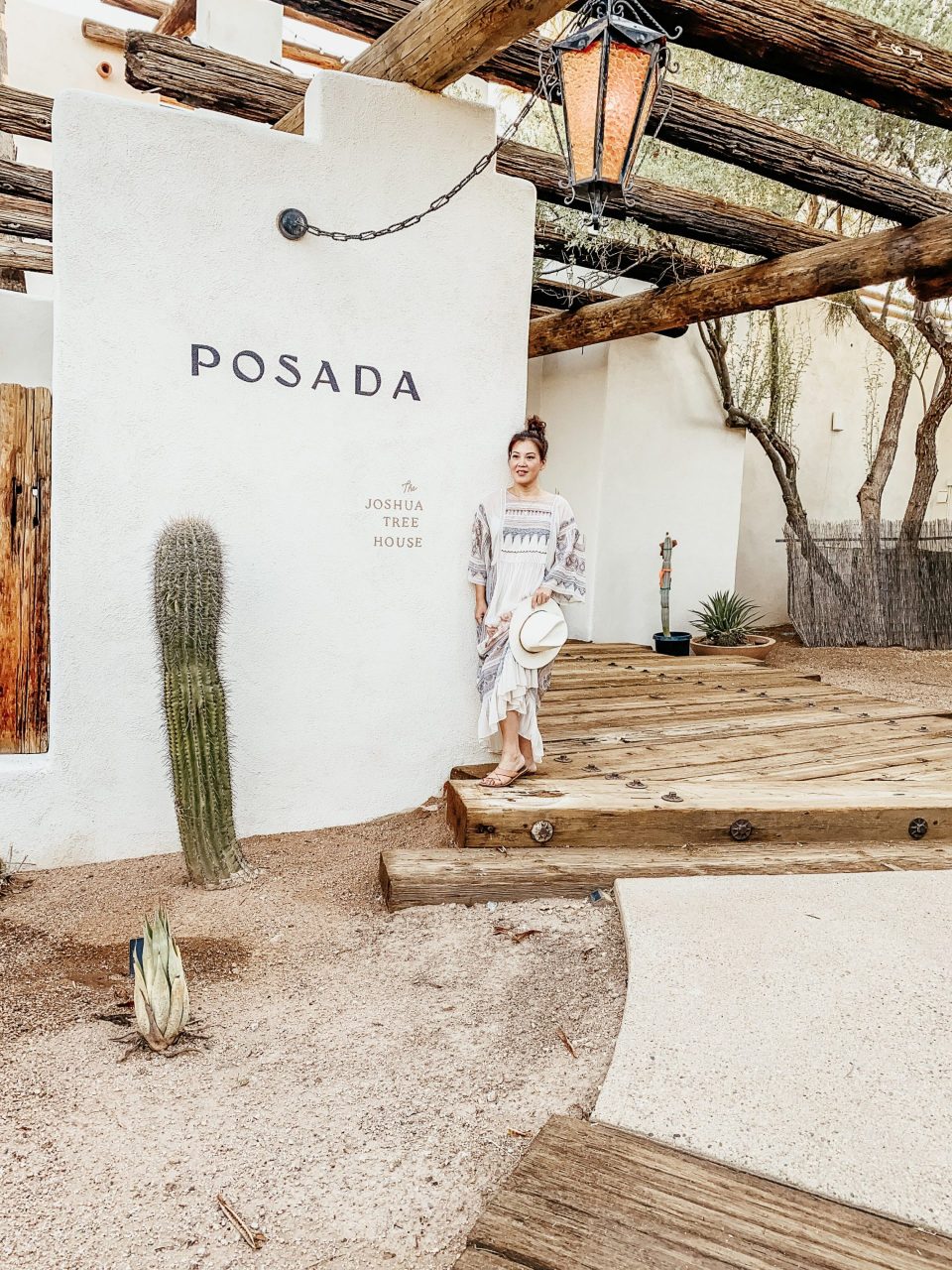 Anita on a rustic porch, beside the sign for the Posada 