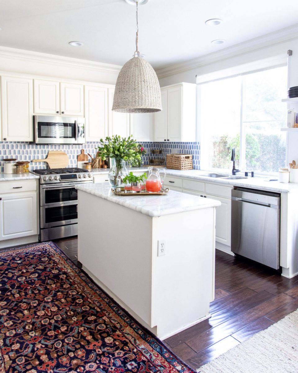 An angle view of our kitchen, with island, rug, and pendant lamp