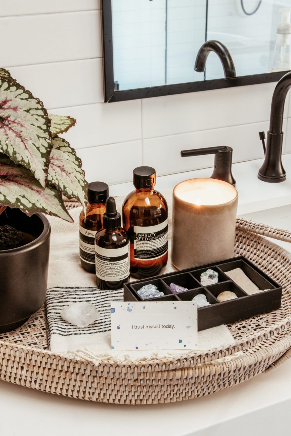 A few bath products beside a candle and a tray of crystals. A meditation card reads: "I trust myself"