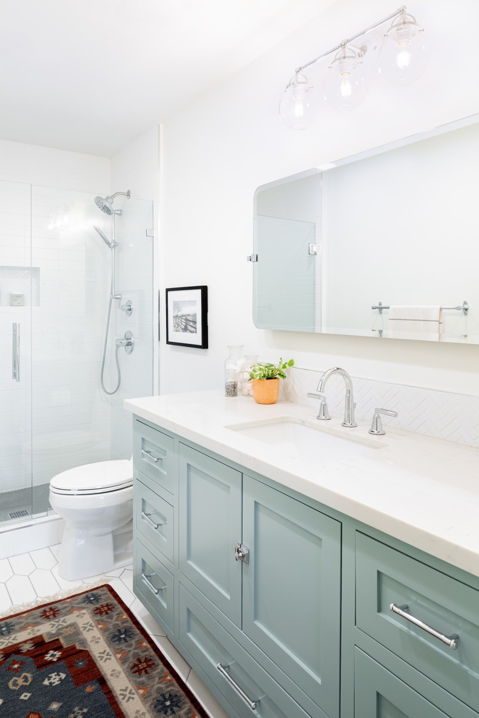 Blue-green cabinets with a white counter, beveled mirror, and chrome fixtures.