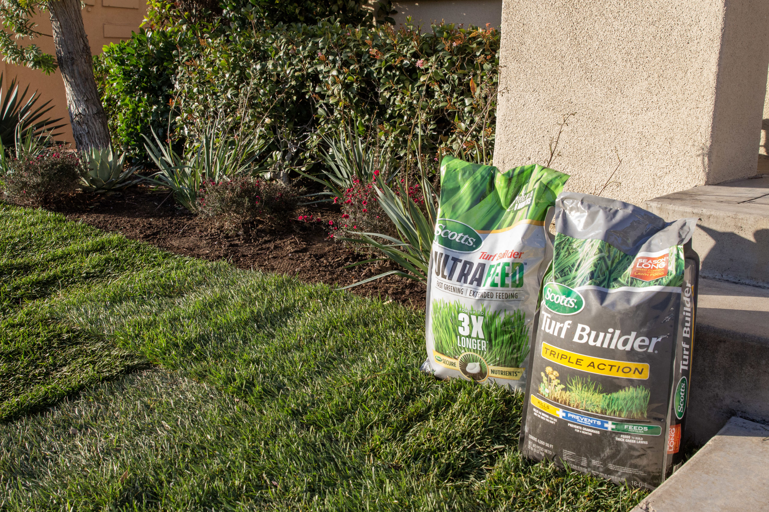 A freshly sodded yard with bags of fertilizer near the landscaping