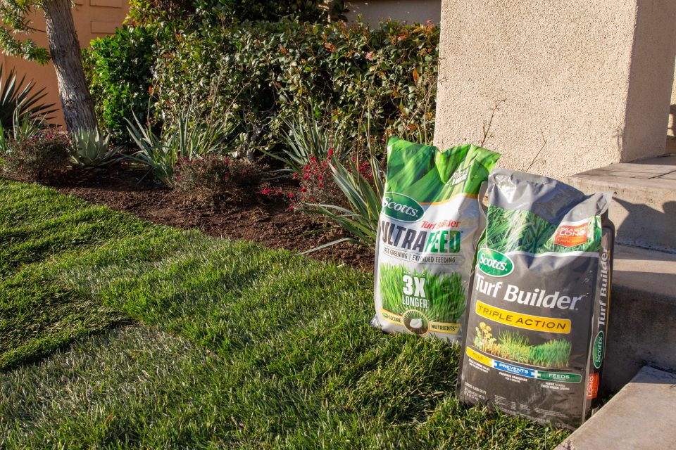 A freshly sodded yard with bags of fertilizer near the landscaping