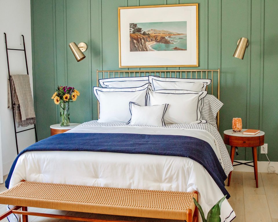 a soft blue and white bed against a relaxing green board and batten