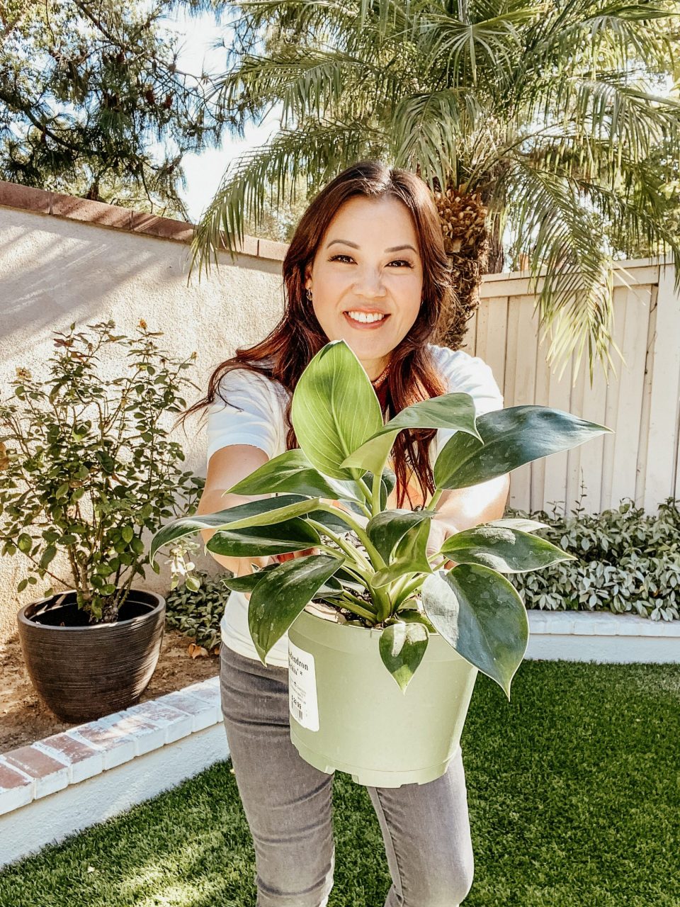 Anita in the backyard, holding out a plant