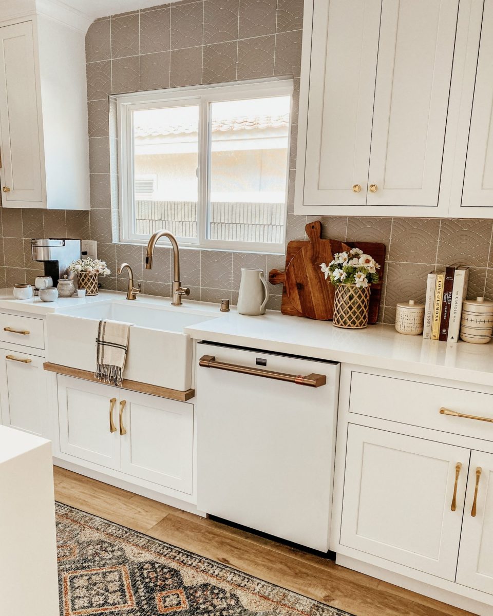 white shaker style cabinets with gold, faceted drawer pulls, and grey textured backsplash