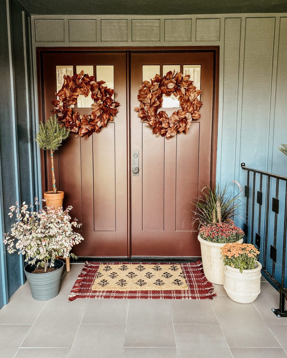 The door is a lovely bronze, highlighted by the surrounding plants and fall wreaths