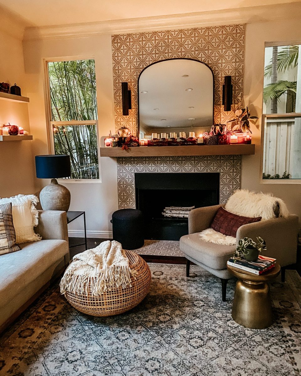 The living room is moody, lit with glowing candles on the mantle and shelves