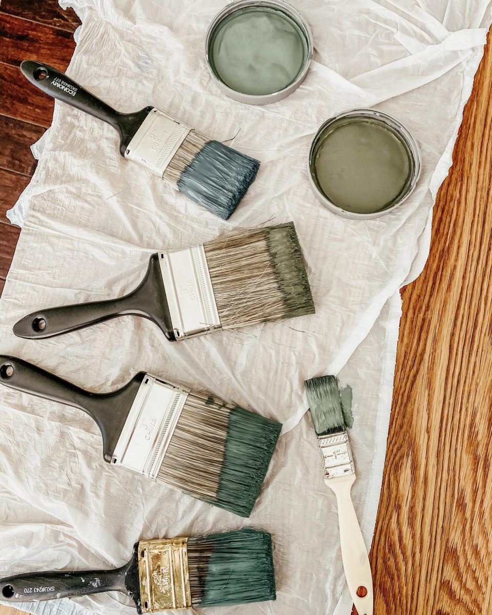 Paintbrushes dipped in varying shades of muted blues and green