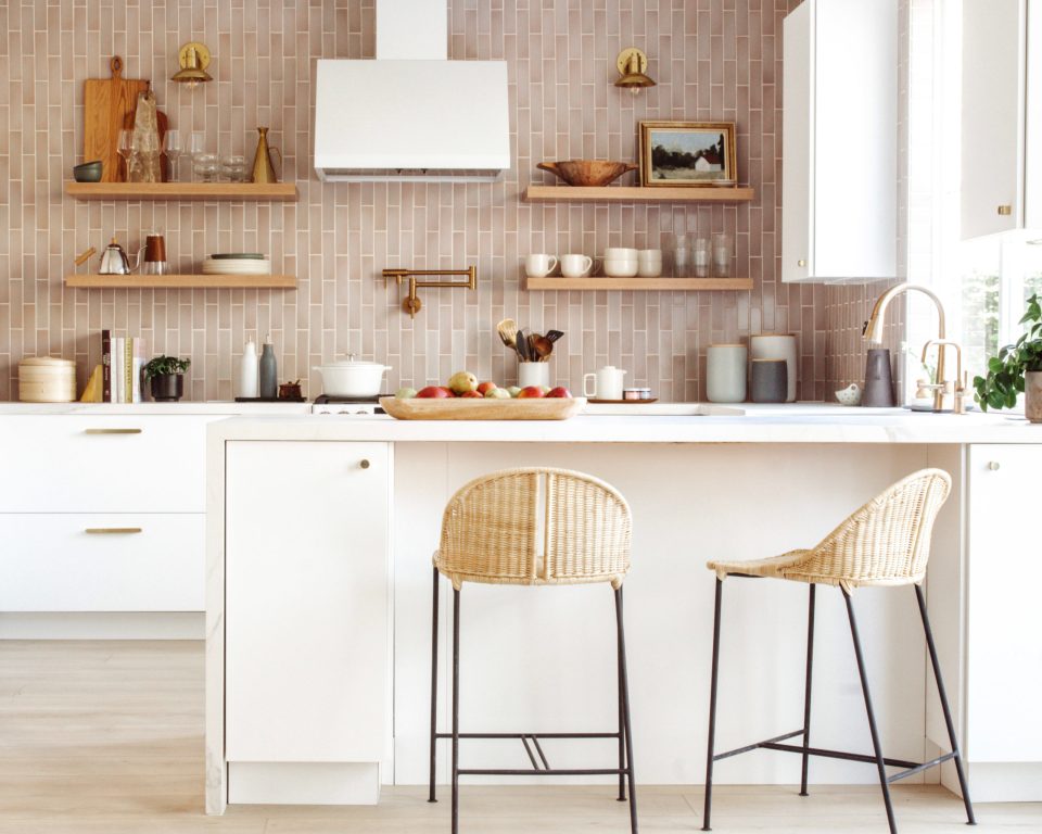 A holistic look at the modern kitchen, with mauve tile, white cabinets and countertops, and wooden and rattan accents. 