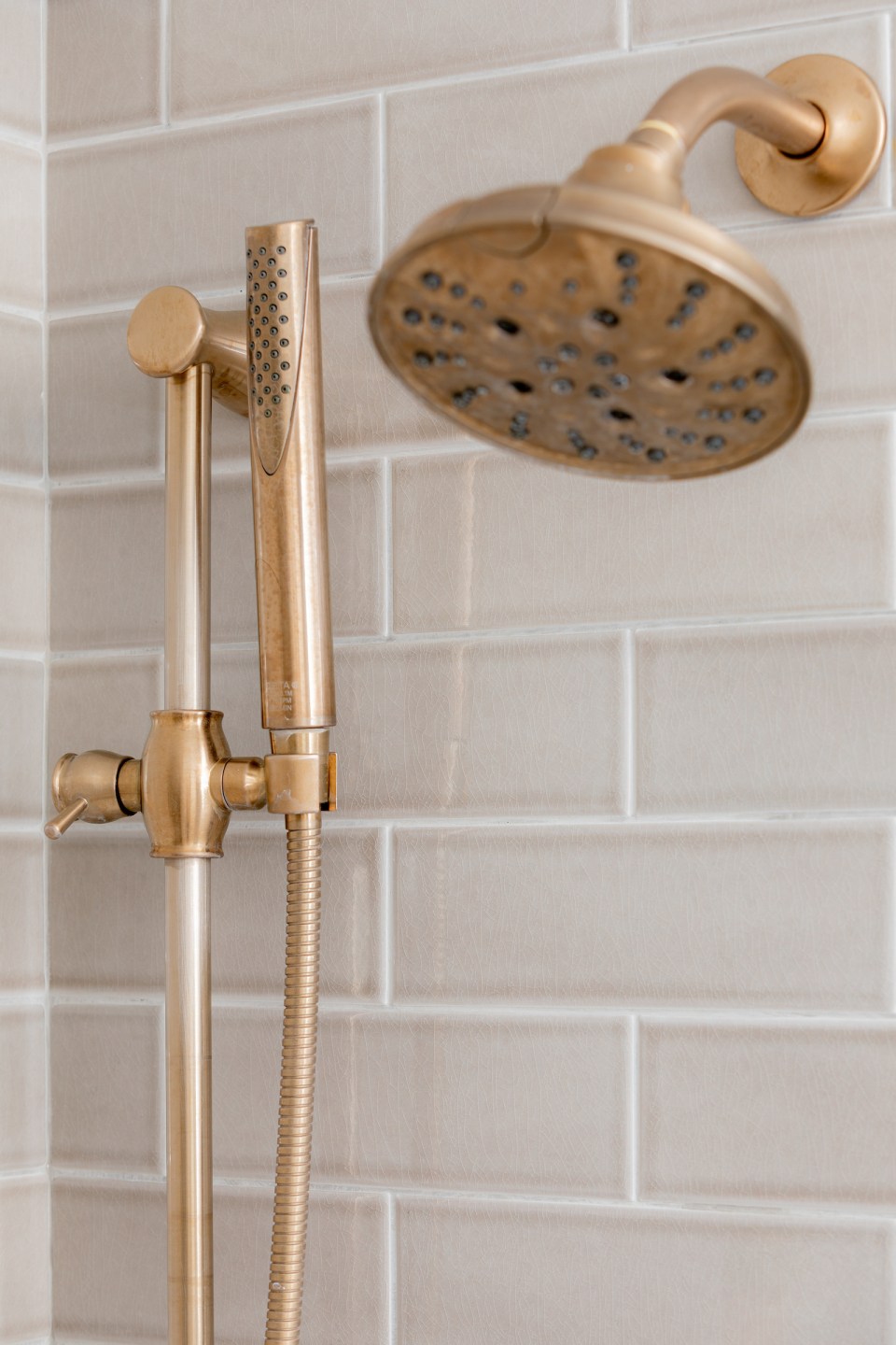 A close up of Detla's hand shower in a brass finish paired with with Dorval shower head 